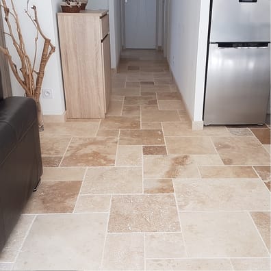 Carrelage aspect pierre beige nuancé dans cuisine moderne avec mobilier bois clair et électroménagers inox