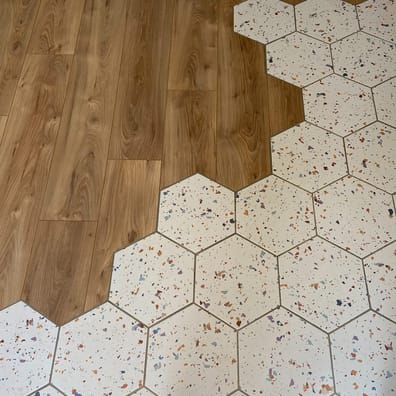 Carrelage Terrazzo multicouleur avec éclats variés 25x30 cm transition vers parquet en chêne clair dans un intérieur moderne