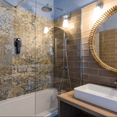Carrelage effet tissu beige marbré 50x100 cm dans une salle de bain tons marron avec miroir rond et douche moderne
