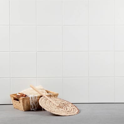 Carrelage blanc uni 10x10 cm sur une salle de bain tons clairs avec panier et accessoires de toilette