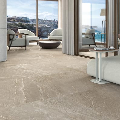 Carrelage effet pierre gris veiné 80x80 cm dans un salon moderne aux tons neutres avec mobilier contemporain et vue sur la mer