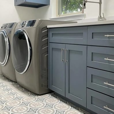 Carreaux de ciment multicouleur avec motifs géométriques 20x20 cm dans une buanderie aux meubles gris, près dune laveuse et séch
