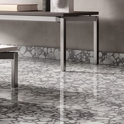Carrelage Terrazzo gris avec éclats blancs 60x60 cm dans un salon moderne aux murs gris et une table en verre et métal