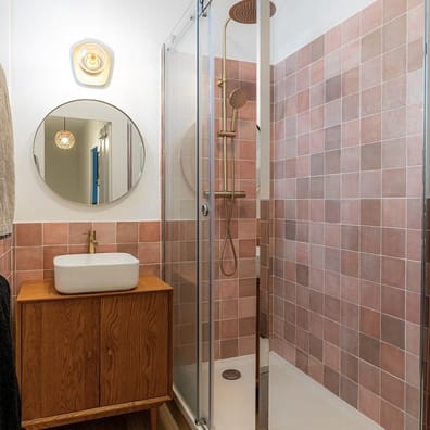 Carrelage effet bois beige 20x120 cm dans une salle de bain tons crème meuble en bois vasque blanche miroir rond luminaire doré