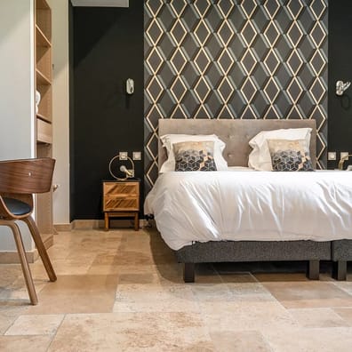 Carrelage aspect pierre beige nuancé sans motifs dans une chambre avec murs noir et décor géométrique, mobilier bois et lit doub