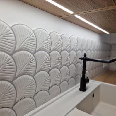 Carrelage uni blanc avec motifs de feuilles en relief 30x30 cm dans une cuisine moderne sur des meubles blancs et bois avec robi