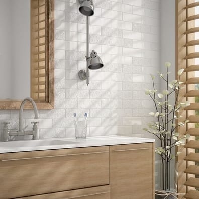 Carrelage uni blanc avec motifs discrets dans une salle de bain épurée aux meubles bois clair et accessoires chromés