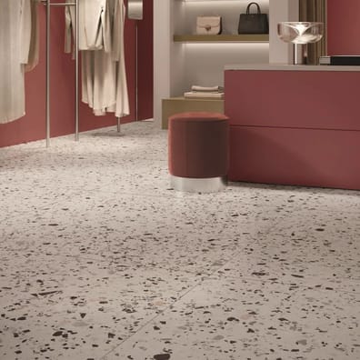 Carrelage Terrazzo blanc éclats multicolores 60x60 cm dans boutique mode murs rose tabourets ronds brun