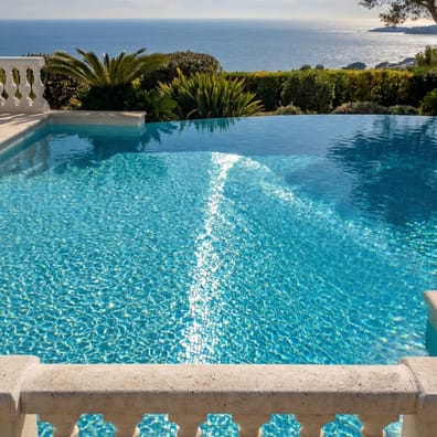 Carrelage uni bleu azur 30x30 cm dans une piscine extérieure entourée de végétation et de balustrades blanches