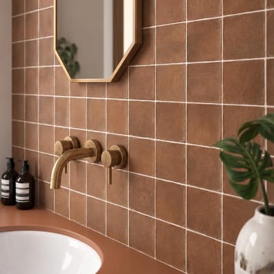 Zellige rouge brillant 10x10 cm sur le mur de la salle de bain tons neutres avec vasque, miroir et luminaire suspendu