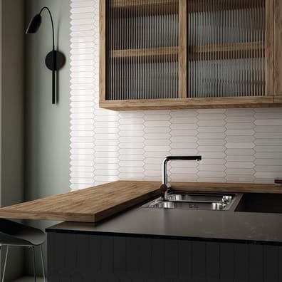 Carrelage uni blanc sur le mur de la cuisine avec armoires en bois et plan de travail gris, évier inox, dans un décor épuré et m