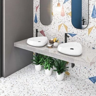 Carrelage Terrazzo multicouleur avec fragments bleus roses beiges dans salle de bain grise avec double vasque blanche sur plan d