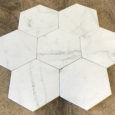 Carrelage aspect marbre blanc avec veines grises, forme hexagonale, sur fond beige.