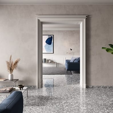 Carrelage Terrazzo gris avec nuances et éclats blancs 60x60 cm dans un salon sobre avec canapé bleu, table basse métallique, pla