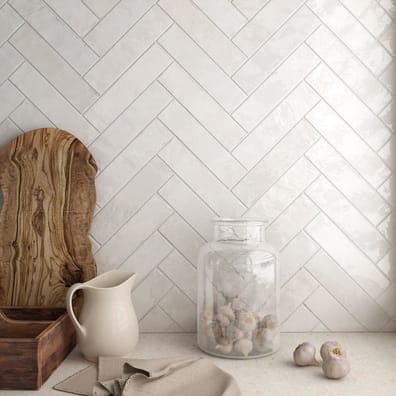 Carrelage Zellige blanc en chevron sur mur de cuisine beige avec accessoires en bois et verre