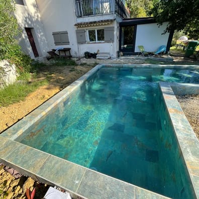 Carrelage pierre multicouleur 30x60 cm dans une piscine extérieure entourée de verdure