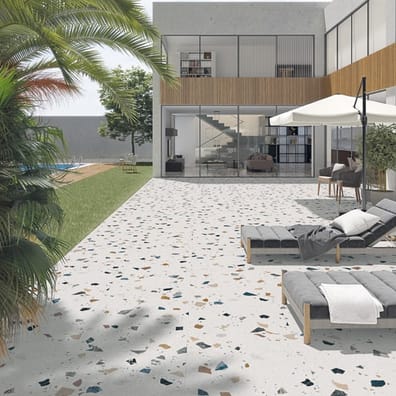 Carrelage Terrazzo blanc parsemé de motifs colorés 60x60 cm dans une cour extérieure tons neutres avec mobilier de jardin et vég