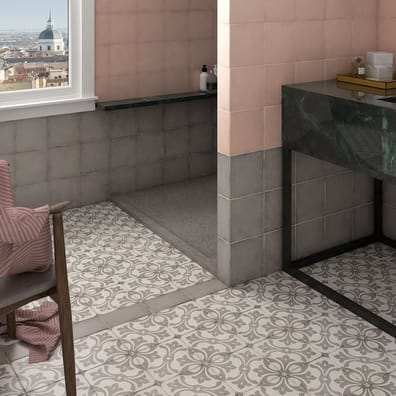 Carreau de ciment gris avec motifs floraux 20x20 cm dans une salle de bain tons pastel, meubles en marbre vert, fauteuil et acce