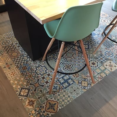 Carreau de ciment multicouleur motifs géométriques et floraux 30x30 cm sous table avec chaises vertes sur fond bois et murs blan