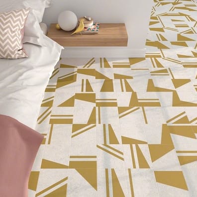 Carrelage effet pierre or avec motifs géométriques 20x20 cm sur sol dune chambre tons blancs et beige avec lit et coussins