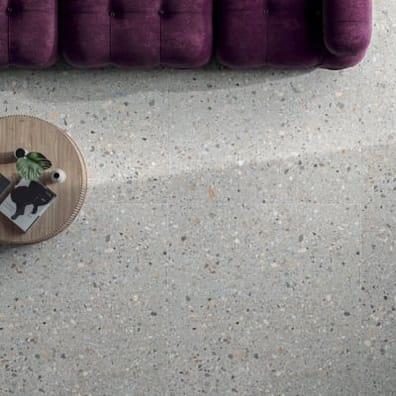 Carrelage Terrazzo blanc avec nuances de gris 60x60 cm sur un sol de salon, canapé pourpre, table basse en bois