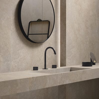 Carrelage effet pierre beige nuances claires et foncées 60x120 cm dans une salle de bain ton sur ton avec miroir rond et robinet