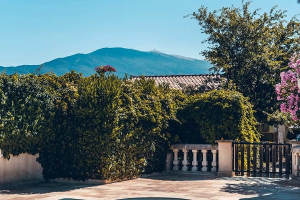 Carrelage effet travertin beige sur terrasse extérieure avec piscine entourée de verdure et montagnes