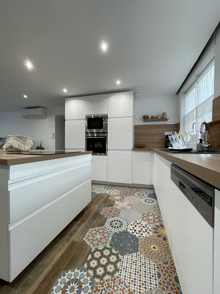 Carreau de ciment terracotta avec motifs variés 30x30 cm sur un sol de cuisine blanche avec bois et mobilier intégré