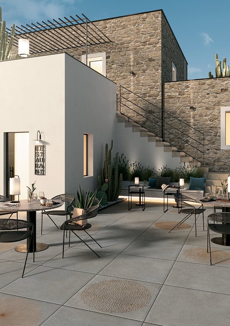 Carrelage pierre gris nuancé motifs circulaires 60x60 cm dans un patio extérieur tons neutres avec mobilier moderne et plantes
