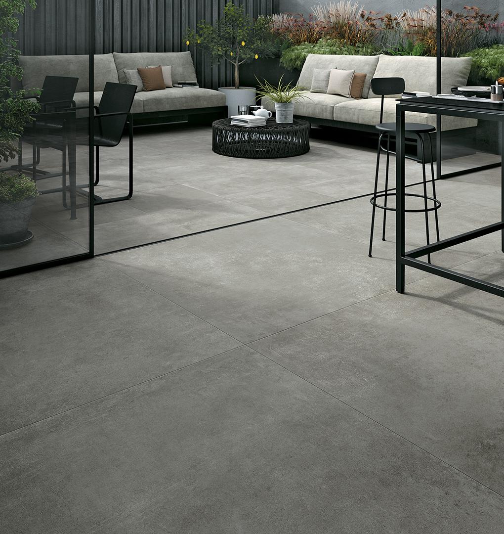 Carrelage effet pierre gris nuances sobres 60x60 cm dans espace extérieur moderne avec mobilier élégant verts et gris