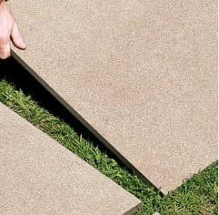 Carrelage effet pierre gris clair uni 60x60 cm sur un extérieur avec herbe verte en bordure