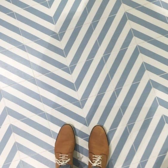 Carreau de ciment bleu clair et blanc motifs géométriques chevrons 20x20 cm sur un sol avec chaussures marron