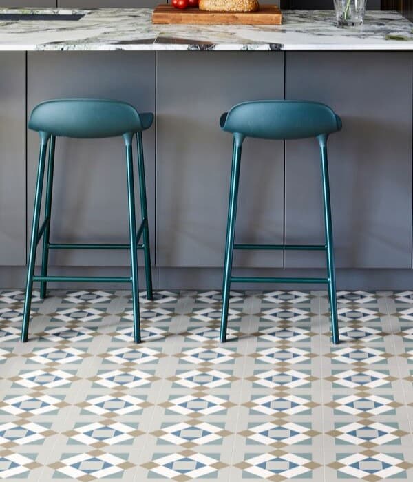 Carreau de ciment vert avec motifs géométriques 20x20 cm dans une cuisine moderne sur plancher bois tabourets hauts verts comptoir en marbre gray