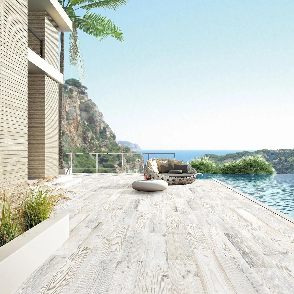 Carrelage effet bois marron clair veiné 15x90 cm sur une terrasse extérieure beige avec piscine et vue sur mer