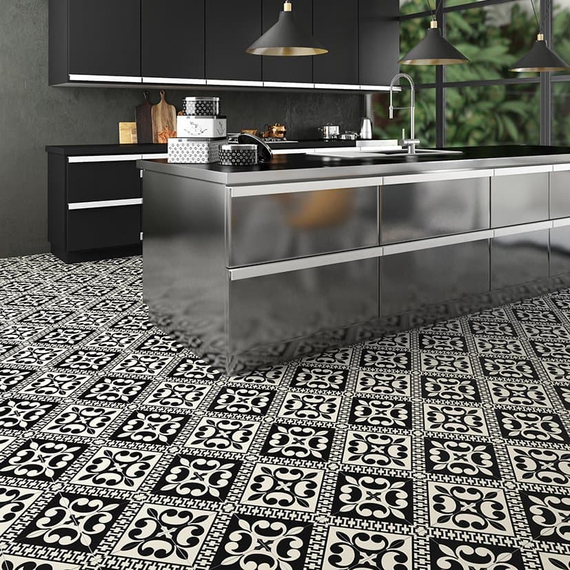 Carreau de ciment noir et blanc à motifs 20x20 cm sur un sol de cuisine moderne avec meubles noirs et plans de travail en inox