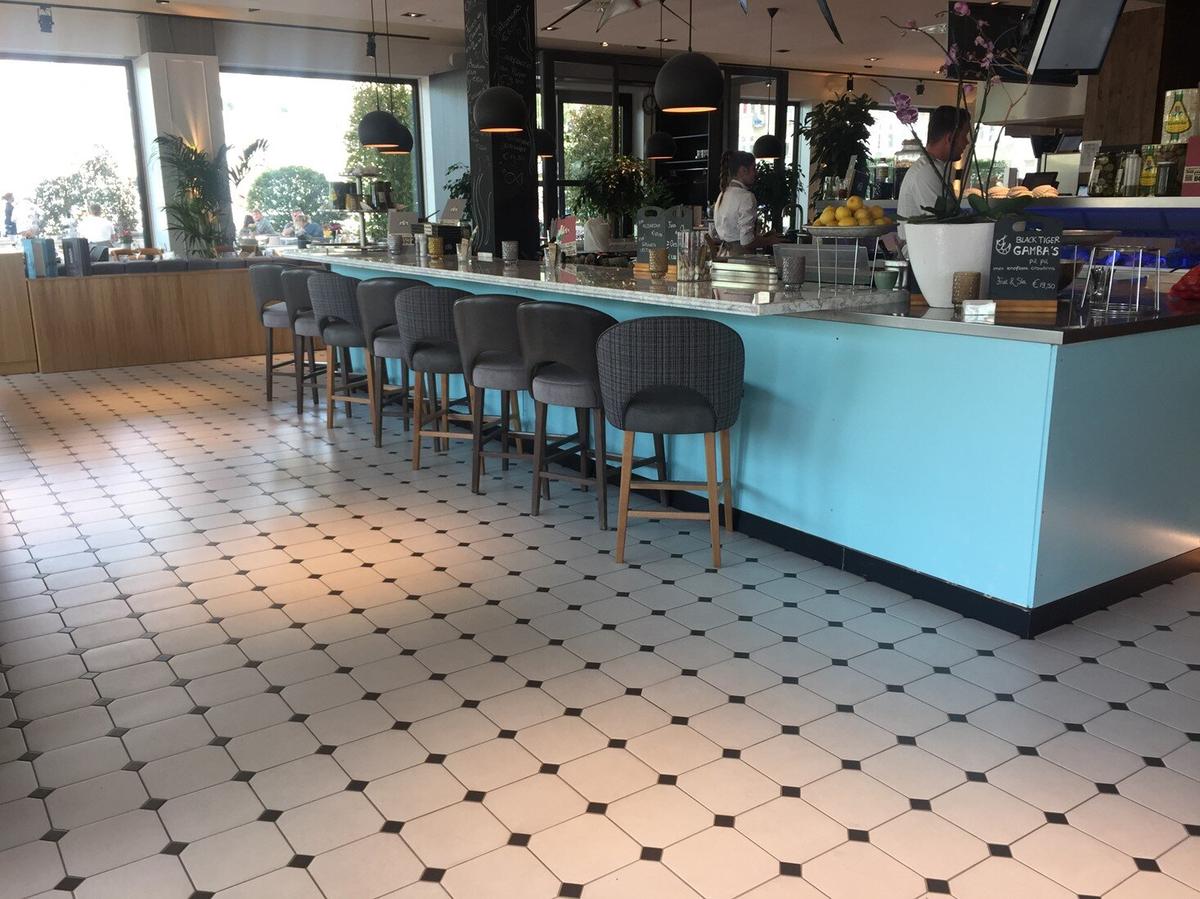 Carrelage uni multicouleur sans motifs 20x20 cm dans un café moderne avec plancher en bois et mobilier bleu et gris