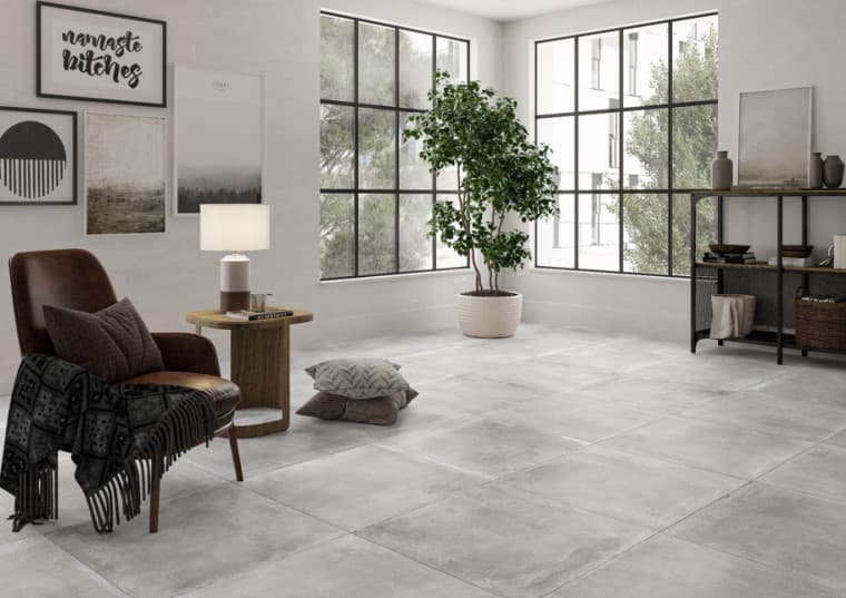 Carrelage aspect béton gris sans motifs taille 60x60 cm dans un salon éclairé nuances de blanc mobilier moderne plante fenêtres larges