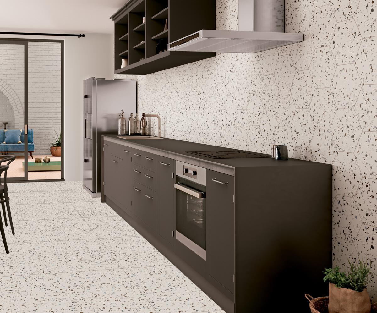 Carrelage Terrazzo blanc avec éclats noir gris 60x60 cm dans une cuisine moderne avec meubles gris plan de travail noir, touches de vert des plantes