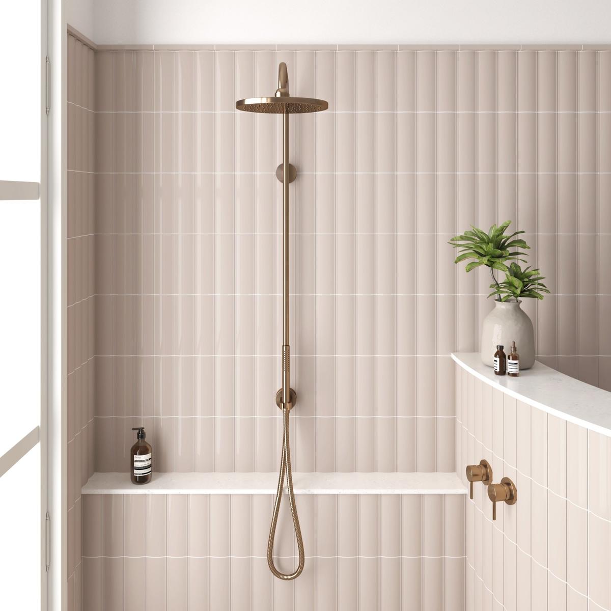 Carrelage uni rose dans une salle de bain aux tons clairs avec douche dorée et éléments de décoration verts
