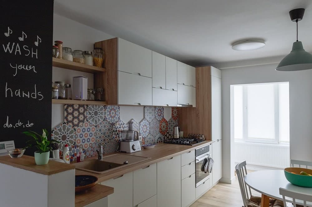 Carreau de ciment terracotta et multicolore motifs divers 30x30 cm dans une cuisine blanche et boisée avec étagères et appareils électroménagers