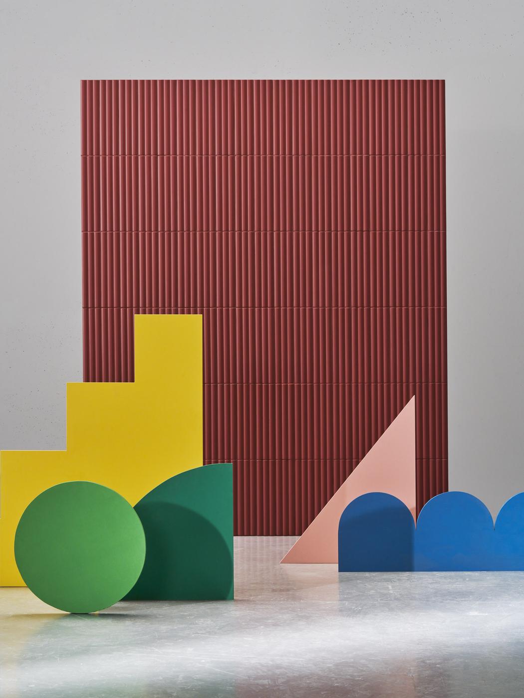 Carrelage uni rouge sans motifs sur mur dans espace moderne avec sol en béton et formes géométriques colorées