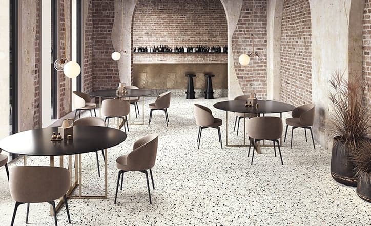 Carrelage Terrazzo blanc avec éclats de couleurs 80x80 cm dans un café aux murs en briques et mobilier moderne brun