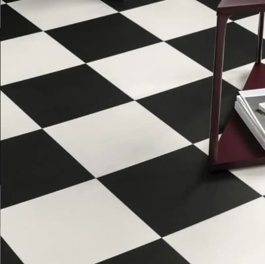 Carrelage uni noir et blanc dans une pièce avec mobilier en bois sombre sur une surface brillante