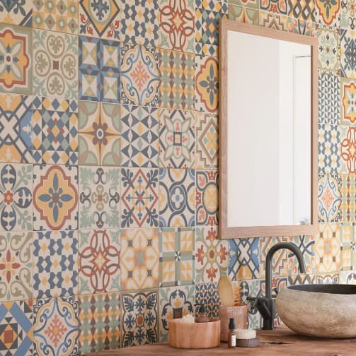 Carreau de ciment multicouleur motifs géométriques et floraux 30x30 cm dans une salle de bains tons chauds avec vasque en pierre et accessoires en bois