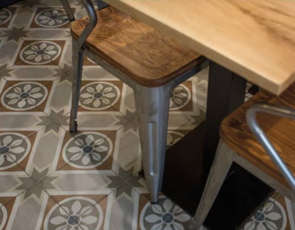Carreau de ciment beige avec motifs géométriques 20x20 cm sous table en bois dans café nuances de marron et gris