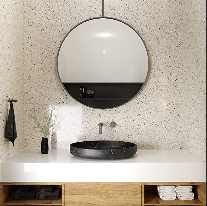 Carrelage Terrazzo blanc avec éclats de couleurs dans une salle de bain épurée blanche avec vasque noire et miroir rond