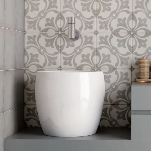 Carreau de ciment gris à motifs floraux 20x20 cm sur un mur de salle de bain gris clair avec lavabo moderne blanc