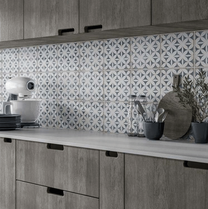 Carreau de ciment bleu motifs géométriques blancs 20x20 cm sur crédence cuisine tons gris avec ustensiles et plante