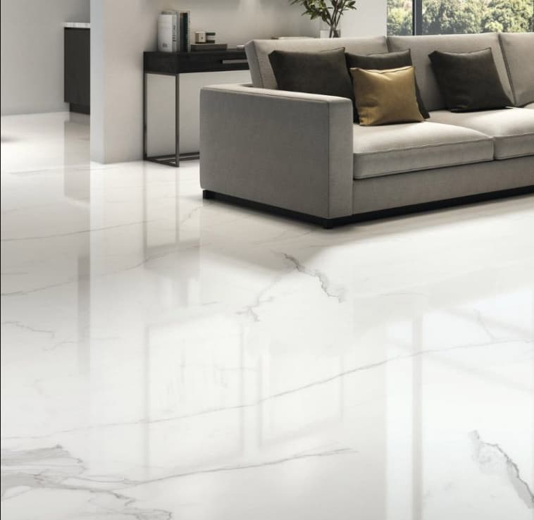 Carrelage marbre blanc avec veinures grises 60x120 cm dans salon moderne aux murs gris, canapé gris et coussins dorés