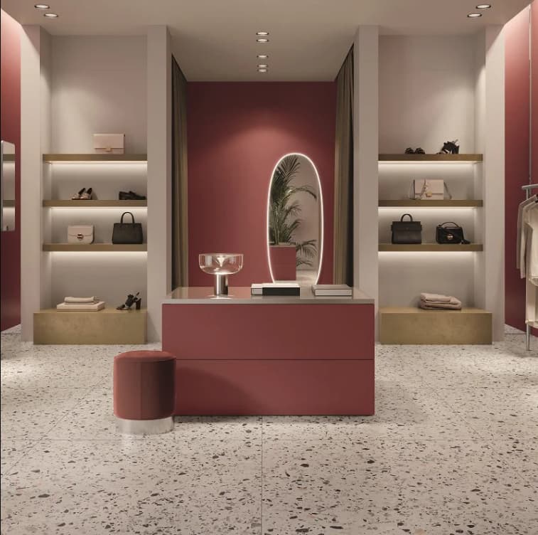 Carrelage Terrazzo blanc éclats colorés 60x60 cm dans un magasin nuances de rose étagères produits mode sièges élégants